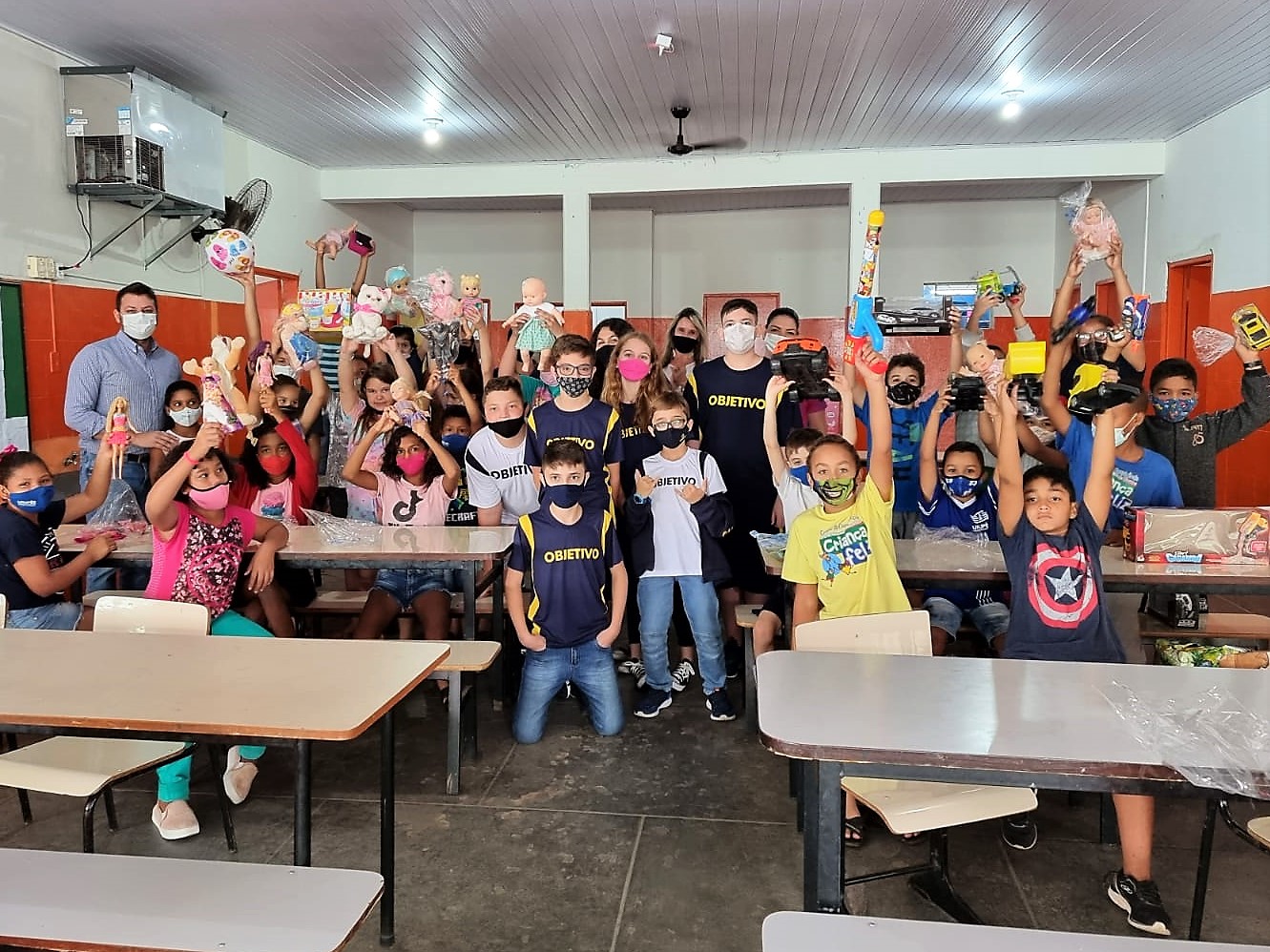 Participantes do Projeto Criança Feliz recebendo o presentes dos alunos do  Colégio Objetivo - Imagem Divulgação