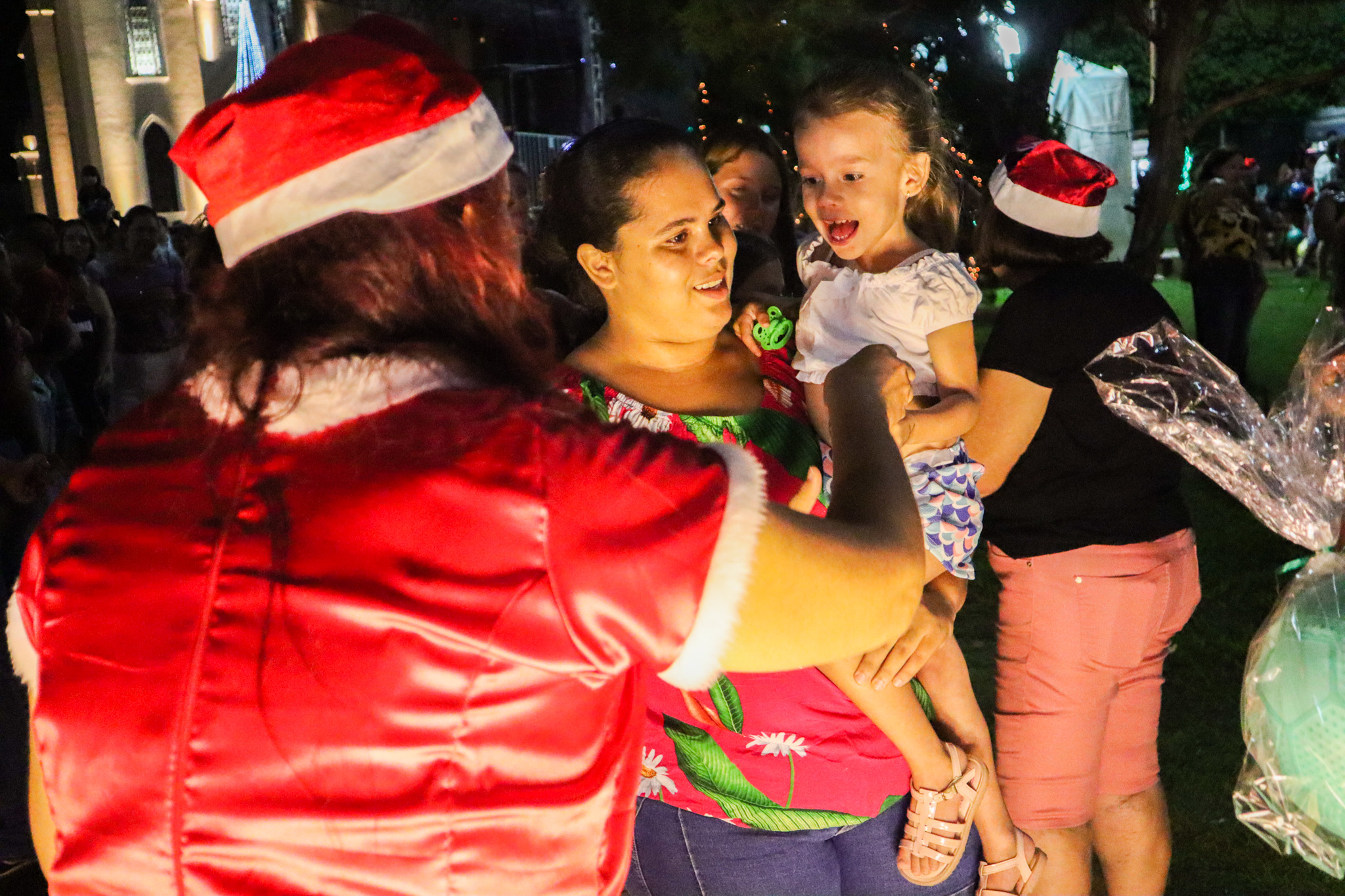 Mamãe Noel distribui brinquedos a criança. Foto: Thomas Volpato Moutropoulos / Prefeitura Municipal de Urupês