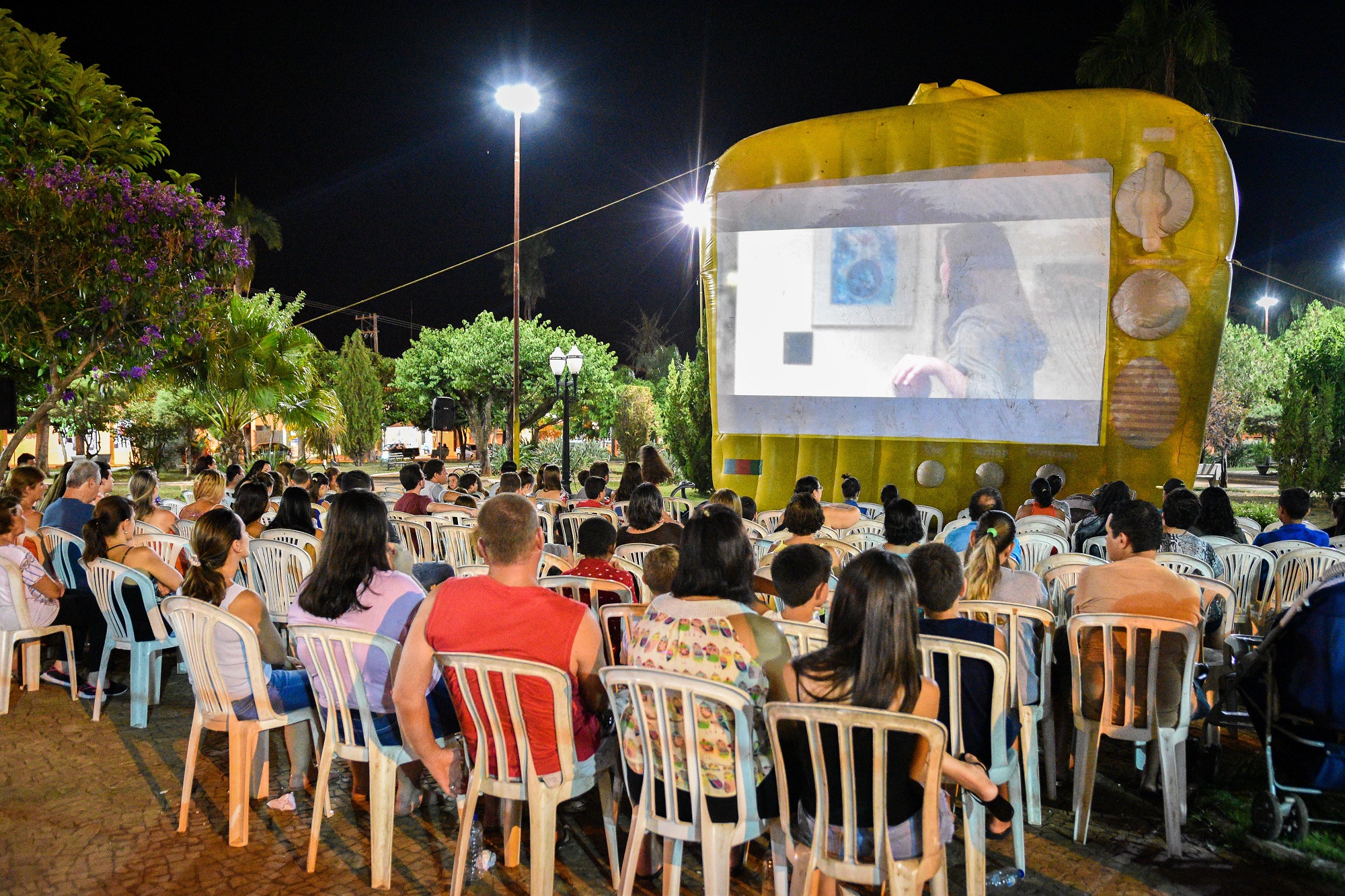 Pessoas assistem a sessão de cinema ao ar livre em Urupês. Foto: Luís Fernando da Silva / Prefeitura de Urupês.