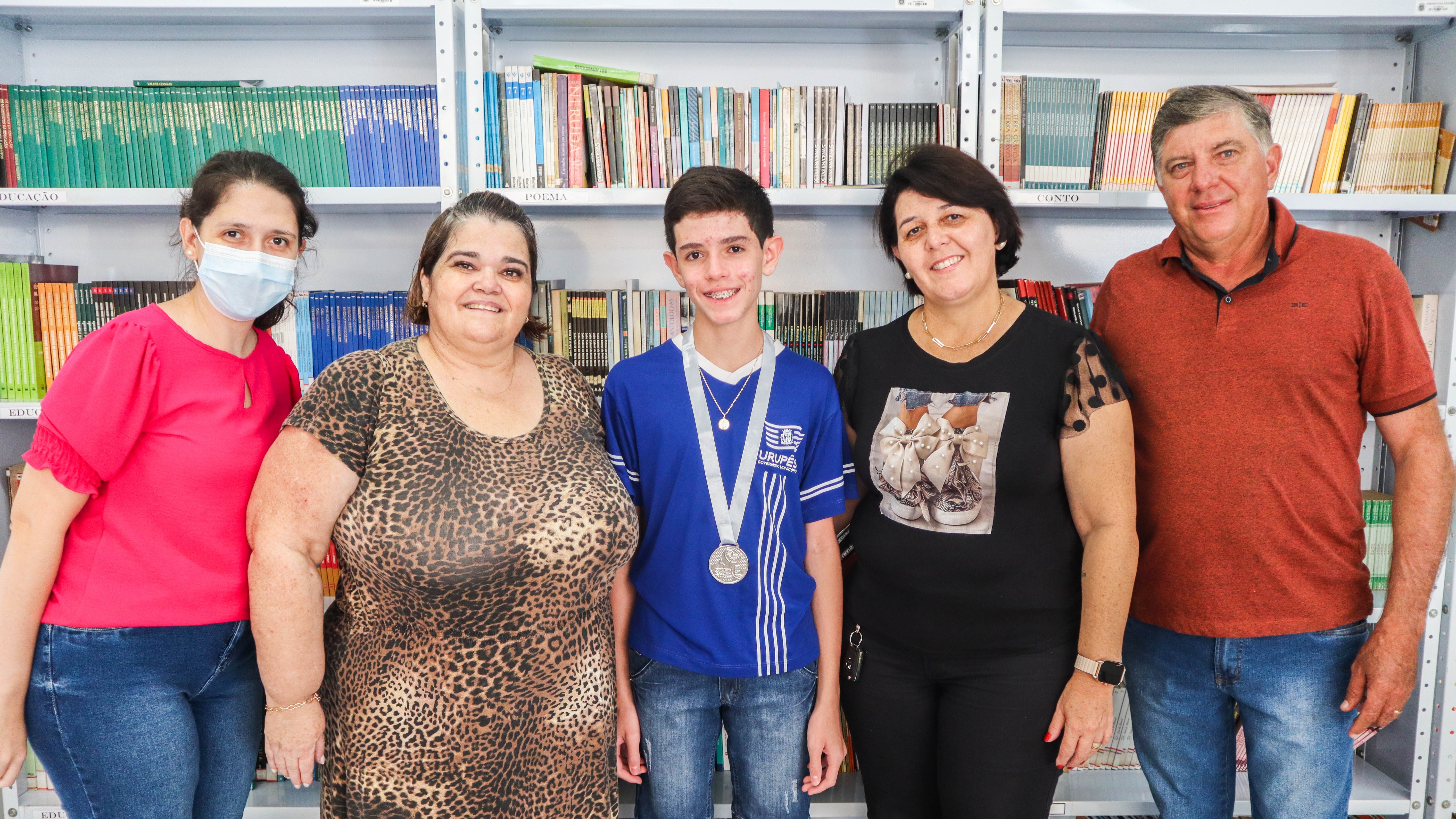 Arthur recebe a medalha, com a presença da professora Priscila Barata, da vice-diretora Rita Simioni e de seus pais. Foto: Thomas Volpato Moutropoulos / Prefeitura de Urupês