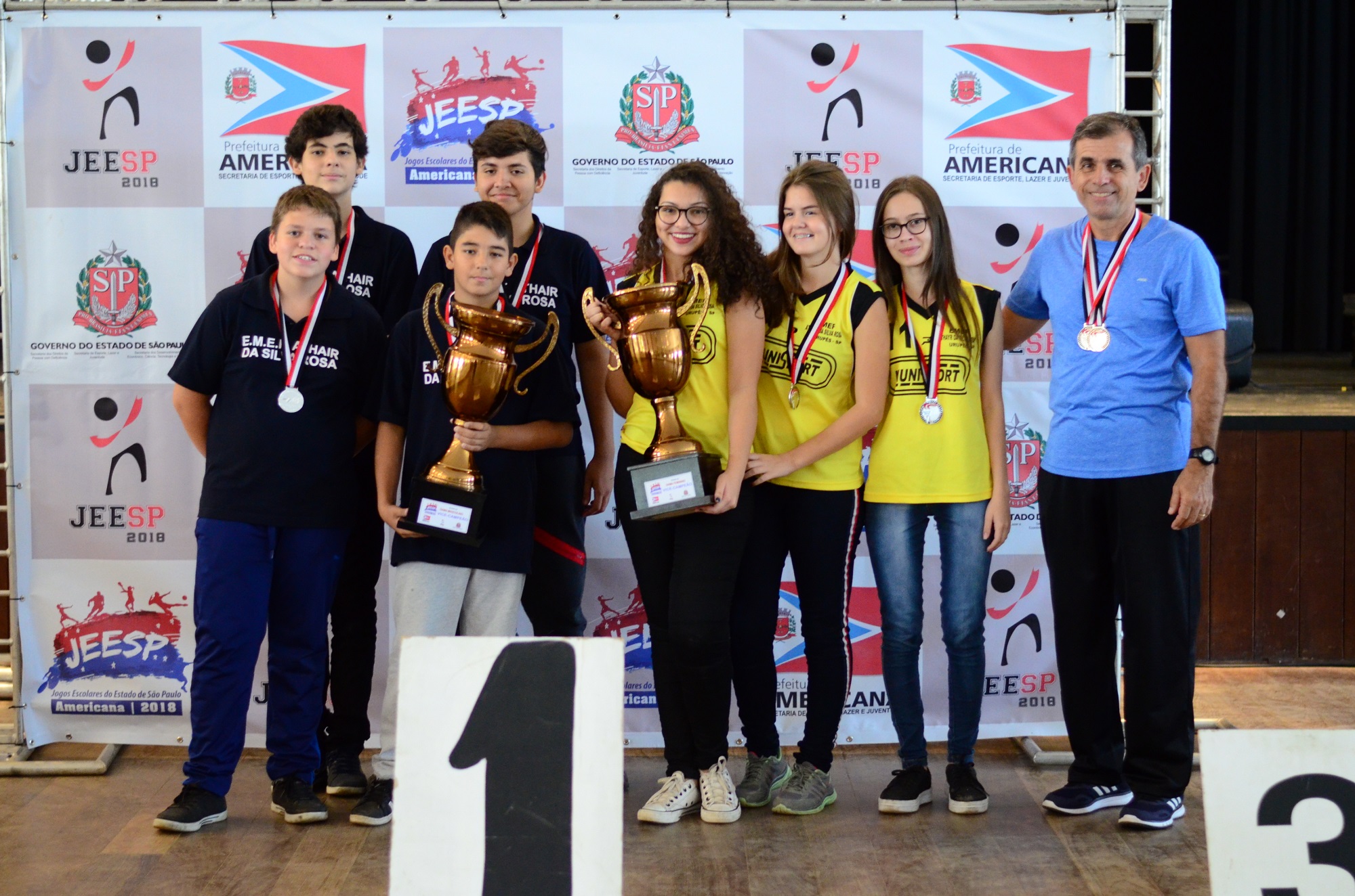 Equipes masculina e feminina de damas, com os troféus, junto ao técnico Edmilson. Foto: Secretaria Estadual de Esporte, Lazer e Juventude